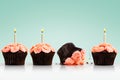 Dropped cupcake in row of cupcakes with candles on green Royalty Free Stock Photo