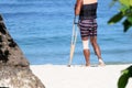 Accident tourist man are walking by crutches on the beach while travel