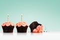 Smashed cupcake in row of cupcakes with candles on green Royalty Free Stock Photo