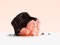 Dropped cupcake with pink frosting on pink background