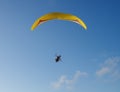 A lone paraglider in blue sky with arms outstretched