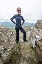 Accomplished smiling woman hiker poses at the summit of LIttle Stony Man, a hike in Shenandoah National Park in Virginia on a
