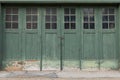 Accordian fold green painted weathered garage doors with windows, creative copy space