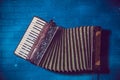 Accordion front side view. musical instrument . old vintage garmon, harmonic on blue wall background Royalty Free Stock Photo