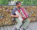 Accordion player busks in front of wall of love locks on the Pont des Arts, Paris, France