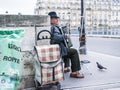Accordion player on Parisian bridge; pigeon strolls by.