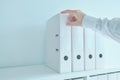 Accountant bookkeeper reaching for document ring binder from the office shelf