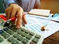 Accountant is calculating financial results with calculator and stack business papers