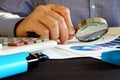 Accountant checking financial report with magnifying glass. Accounting.