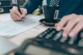 Accountant writing and checking while working on calculator to calculate company data, document and report on desk office. Royalty Free Stock Photo