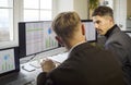 Two analysts reviewing financial data and charts on multiple office monitors Royalty Free Stock Photo