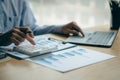 At the accounting desk, an accountant presses a calculator to analyze investment charts to generate monthly financial reports or c Royalty Free Stock Photo