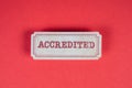 ACCREDITED. Cardboard sticker with text on a red background