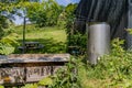 Accumulation of objects in backyard of a farm with wild vegetation on hill in background