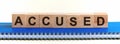 Accused - a word made of wooden blocks with black letters, a row of blocks is located on a blue Notepad. White background, front Royalty Free Stock Photo