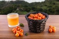 Acerola juice and raw acerolas on wooden table in nature