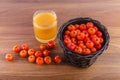 Acerola juice and raw acerolas on wooden table in nature