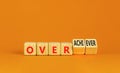 Achiever or overachiever symbol. Businessman turns wooden cubes and changes word Achiever to Overachiever. Beautiful orange