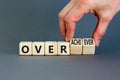 Achiever or overachiever symbol. Businessman turns wooden cubes and changes word Achiever to Overachiever. Beautiful grey table