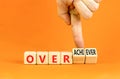 Achiever or overachiever symbol. Businessman turns wooden cubes and changes word Achiever to Overachiever. Beautiful orange