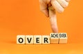 Achiever or overachiever symbol. Businessman turns wooden cubes and changes word Achiever to Overachiever. Beautiful orange