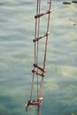 Achieving success. Rope ladder. Jacobs ladder. Rope ladder with wooden steps. Rope over water surface. Rescue or escape