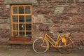 Yellow bike against stone wall and yellow window