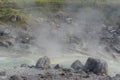 Acidic hot spring stream water with hydrochloric acid emitting steam in mountain valley at Tamagawa Onsen Hot spring in Japan Royalty Free Stock Photo