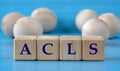 ACLS - acronym on wooden cubes on a blue background with wooden round balls