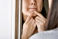 Acne pus, Close up photo of acne prone skin, Woman looking at mirror and hand squeezing her acne cyst. Royalty Free Stock Photo