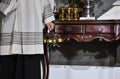 An acolyte, an altar boy who assists the Priest at the Altar during the celebrations, next to a table with several golden ambulae