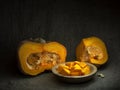 Acorn winter squash, pumpkin, prepared for cooking, cubes with seeds. Life cycle concept. Chiaroscuro, baroque style