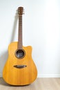 An acoustic dreadnought guitar leaned against the white wall background. Veritcal image copy space Royalty Free Stock Photo