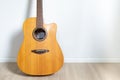 An acoustic dreadnought guitar leaned against the white wall of the room background Royalty Free Stock Photo