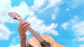 Acoustic Guitar being played by hands against a cloudy sky