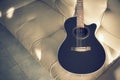 Acoustic guitar black color on sofa cushions