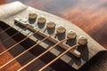 Acoustic guitar bridge with one pins and strings close up with selective shallow focus and blur Royalty Free Stock Photo