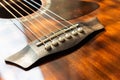 Acoustic guitar bridge with one pins and strings close up with selective shallow focus and blur Royalty Free Stock Photo