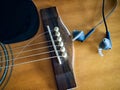 Acoustic guitar with broken guitar strings and earphone Royalty Free Stock Photo