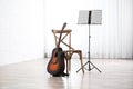 Acoustic guitar, chair and note stand with music sheets Royalty Free Stock Photo