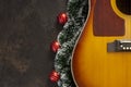 Acoustic guitar and Christmas garland decor with red dekorative balls on dark brown background Royalty Free Stock Photo