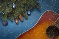 Acoustic guitar and Christmas tree branches with blue dekorative balls on blue background with glitter Royalty Free Stock Photo