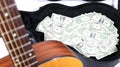 Acoustic guitar corner and neck up close out of focus, money in case, in focus, strong depth of field