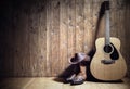 Acoustic guitar, cowboy hat and boots against blank wooden plank panel grunge background with copy space