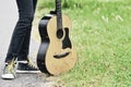 acoustic guitar and feet standing on green grass