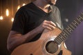 Acoustic guitar in the hands of a guitarist at a concert close-up on a black blurred background