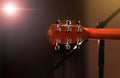 Acoustic guitar head with tuning pegs, neck, frets and fingerboard, back view. Headstock of the guitar over concert stage Royalty Free Stock Photo