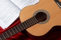 Acoustic guitar and music notes on red fabric, close view of objects Royalty Free Stock Photo