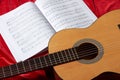 Acoustic guitar and music notes on red fabric, close view of objects Royalty Free Stock Photo