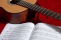 Acoustic guitar and music notes on red fabric, close view of objects Royalty Free Stock Photo